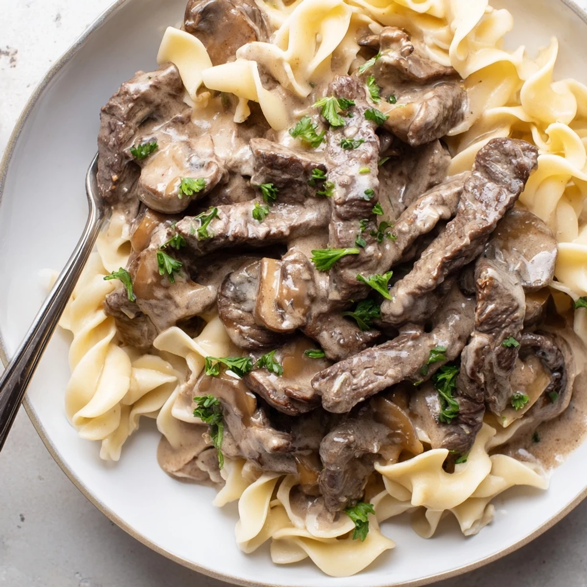Tender strips of beef in rich mushroom sauce, featuring Easy Beef Stroganoff delight.  