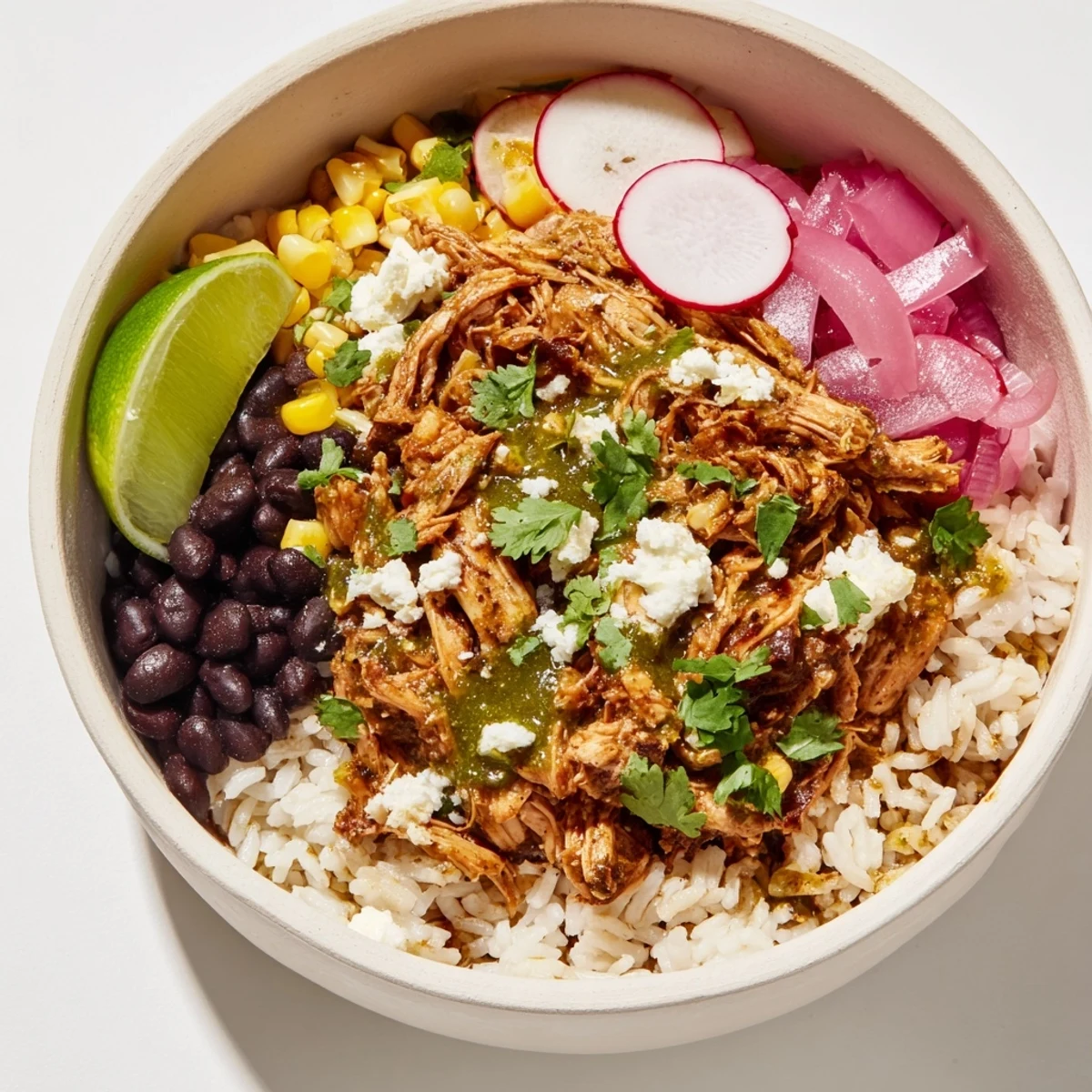 Green Enchiladas Rice Bowl overflowing with chicken, black beans, and vibrant green sauce served in bowls.