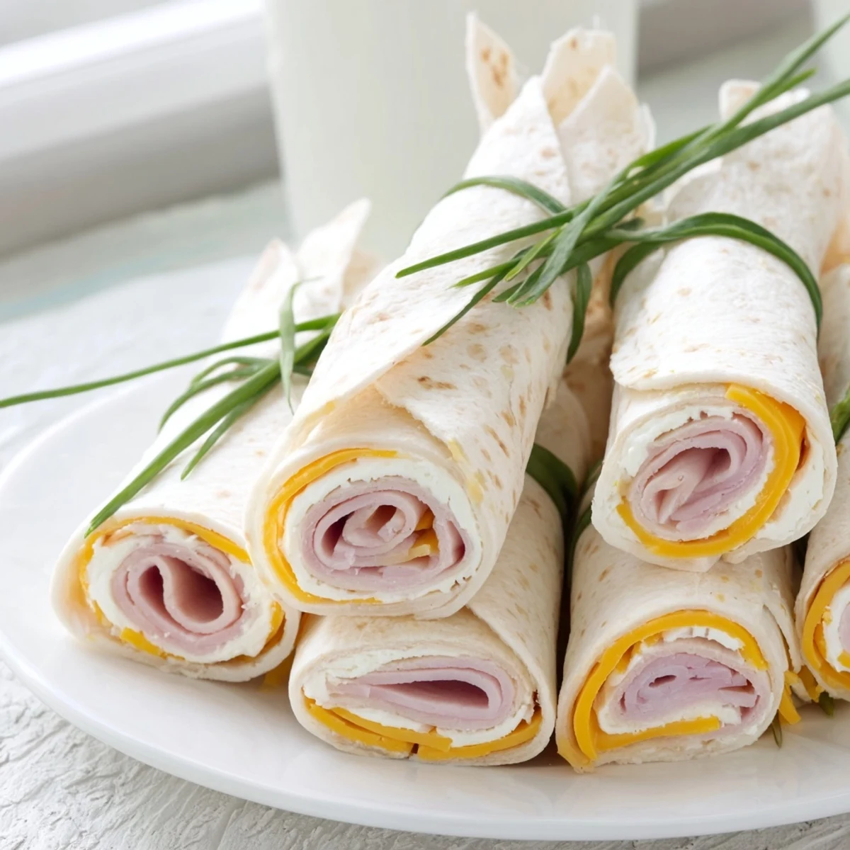 Festive Graduation Cap Diploma Snack Wraps featuring turkey and cheese, tied with chives, ready to serve.