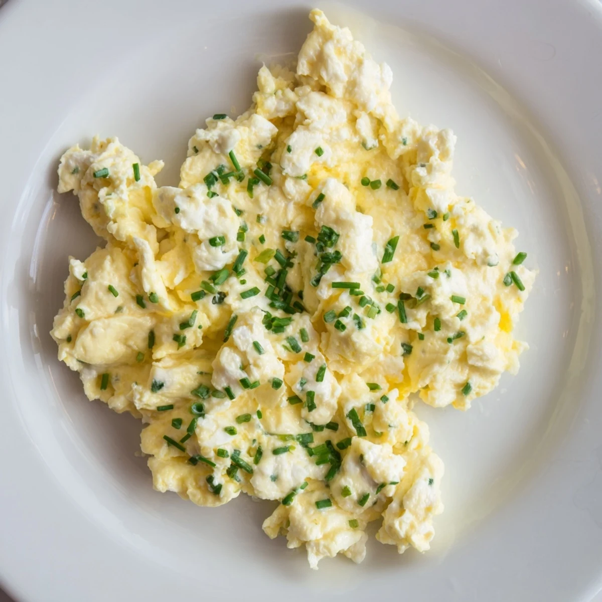 Close-up of freshly cooked cottage cheese scrambled eggs, seasoned and ready, perfect with chives.