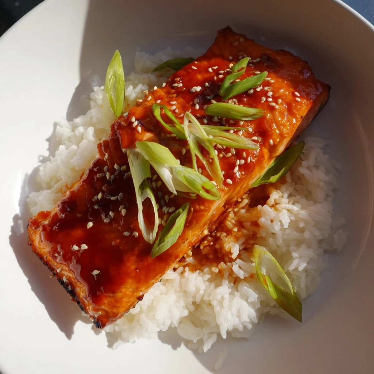 A close-up captures the glazed Sticky Orange Salmon fillets alongside a portion of delicious, buttery rice.