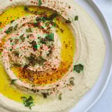 A vibrant close-up shows a Levantine hummus plate, garnished with parsley, a flavorful appetizer.