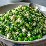 Fluffy couscous mixed with tender spring peas, fresh mint, and lemon dressing for a refreshing Mediterranean side dish.  