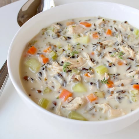 Creamy Chicken and Wild Rice Soup garnished with fresh herbs, perfect for cozy dinners.  