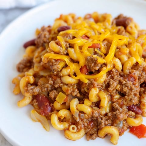 Steaming Cheeseburger Chili Mac Skillet, topped with melted cheddar, ready for a comforting weeknight meal.