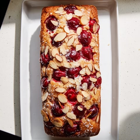 Moist, slice of Cherry Almond Loaf Cake, perfect with coffee, showcasing the cherries and almonds.