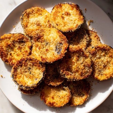 Golden-brown, crispy Eggplant Parmesan Chips are arranged on a baking sheet, ready to devour!