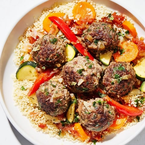 Steaming bowl of North African couscous kefta, rich with spiced meatballs and fragrant vegetables.
