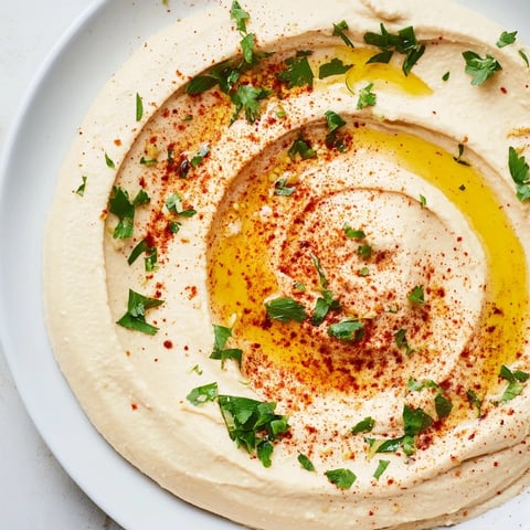 Creamy Levantine hummus plate, drizzled with olive oil and sprinkled with paprika, ready to serve with pita.
