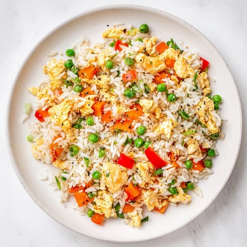Fluffy scrambled eggs and colorful vegetables mingle with savory soy sauce in this classic Egg Fried Rice.
