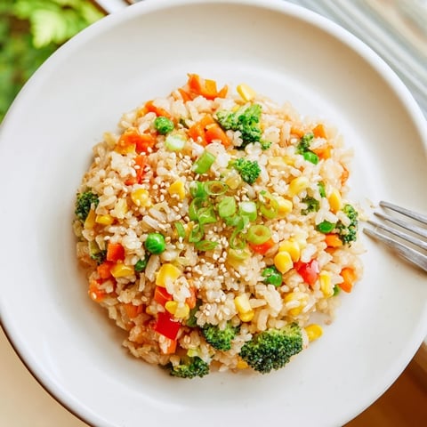 A vibrant bowl of homemade vegetable fried rice packed with colorful carrots, peas, and bell peppers.  