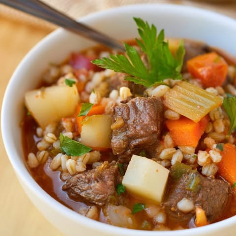 Close-up of a steaming bowl of Beef and Barley Stew, garnished with fresh parsley.