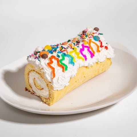 This Ugly Sweater Cake Roll ready to serve, features whimsical sprinkles and joyful festive treats.