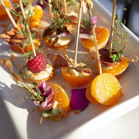 Vibrant Baisers de Minuit cocktail garnish skewers featuring fresh raspberries, pomegranate seeds, and mint.