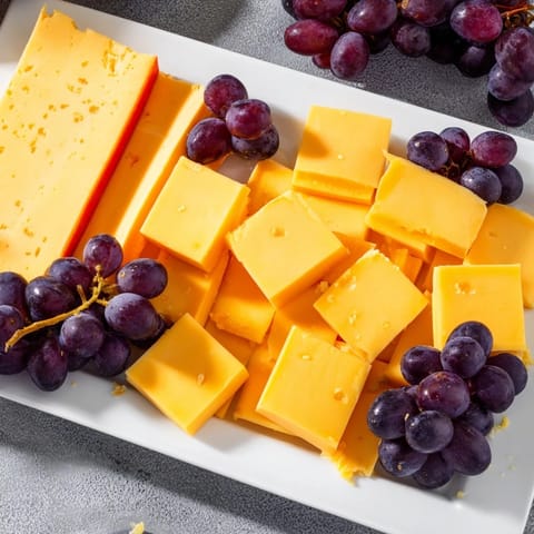 Vibrant Bauhaus Block appetizer featuring red pepper, yellow cheese, and plump, juicy grapes arranged geometrically.