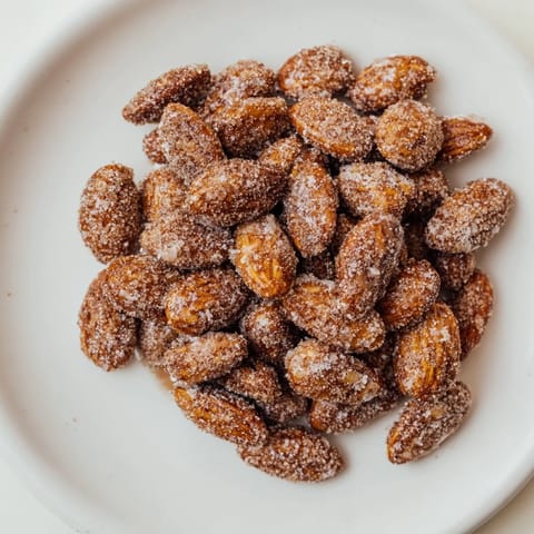 A close-up of beautifully spiced cinnamon roasted almonds: crunchy, sweet, and perfectly golden brown.