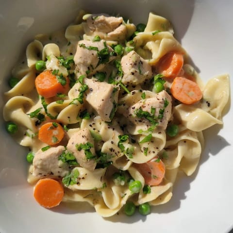 Hearty creamy chicken and egg noodles, with visible vegetables and herbs, ready to be enjoyed.