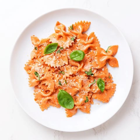 Steaming Tomato Basil Bowtie Pasta served in a rustic bowl, showcasing the velvety sauce clinging to each farfalle and a sprinkle of Parmesan.  