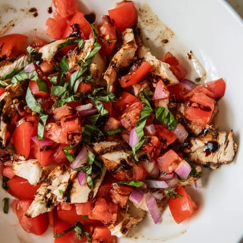 Savory grilled chicken nestled on a bed of mixed greens with a colorful bruschetta topping and shaved Parmesan, ready for a light lunch.  