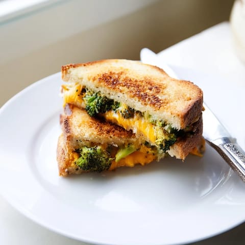 A comforting Roasted Broccoli & Cheddar Grilled Cheese served warm, perfect for pairing with a creamy bowl of tomato soup.