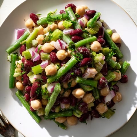 Vibrant Three-Bean Salad featuring crisp celery, red onion, and fresh parsley, served chilled as a refreshing vegetarian side.