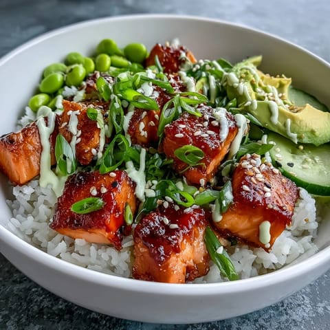 Sriracha mayo drizzles over the Salmon Rice Bowl, adding a creamy, spicy kick to the colorful meal.