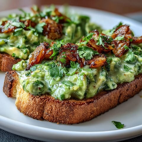 Vibrant chilli-lime avocado toast with creamy mashed avocado, tangy dressing, and crispy shallots on golden sourdough bread.