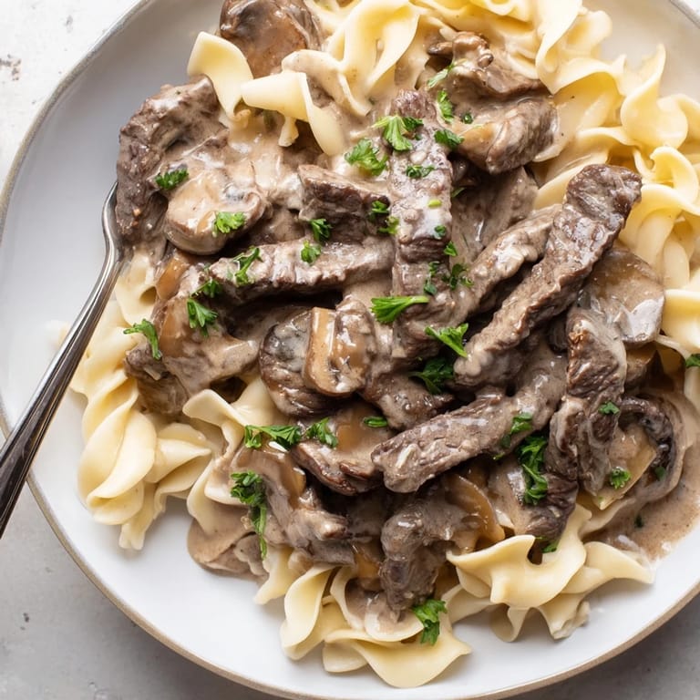 Tender strips of beef in rich mushroom sauce, featuring Easy Beef Stroganoff delight.  
