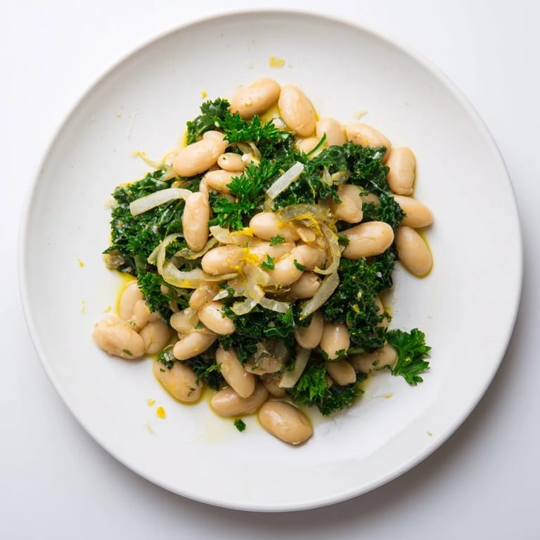 This bowl of garlicky beans with winter greens showcases a comforting, rustic dish on a wooden table.