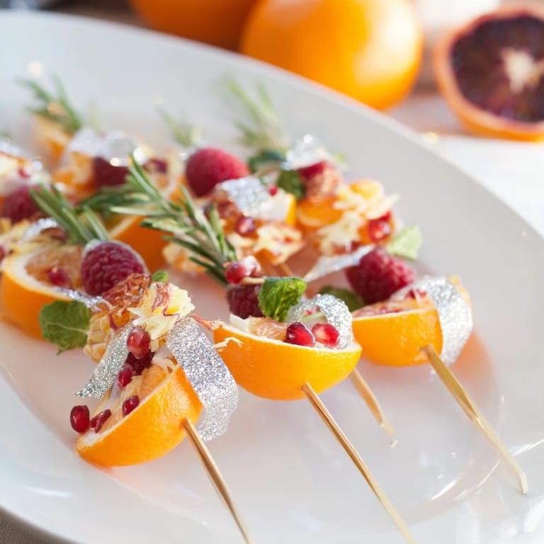 Close-up of elegant Baisers de Minuit, sugared citrus slices and rose petals atop a dark cocktail.