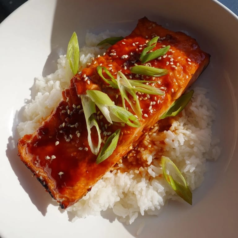 A close-up captures the glazed Sticky Orange Salmon fillets alongside a portion of delicious, buttery rice.
