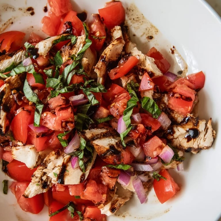 Savory grilled chicken nestled on a bed of mixed greens with a colorful bruschetta topping and shaved Parmesan, ready for a light lunch.  
