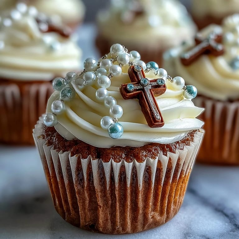 Elegant vanilla mini cupcakes adorned with smooth buttercream and handcrafted fondant rosary toppers, perfect for First Communion dessert tables.