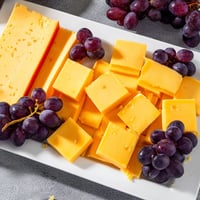 Vibrant Bauhaus Block appetizer featuring red pepper, yellow cheese, and plump, juicy grapes arranged geometrically.