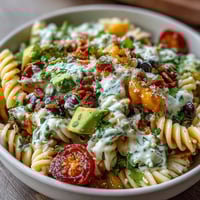 Colorful taco pasta salad with rotini, black beans, corn, and cheddar, topped with crushed tortilla chips and fresh cilantro.