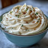 Creamy homemade garlic aioli, rich and garlicky, served in a bowl beside golden fries and fresh vegetables.  